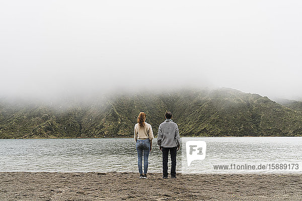 Rear view of couple at lakeshore exploring Sao Miguel Island together in Azores  Portugal