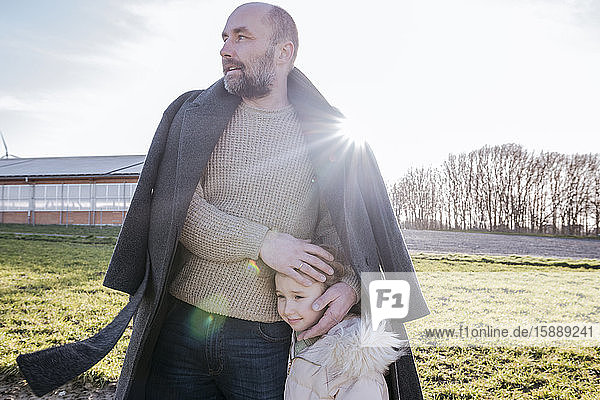 Father and little daughter on a field in winter