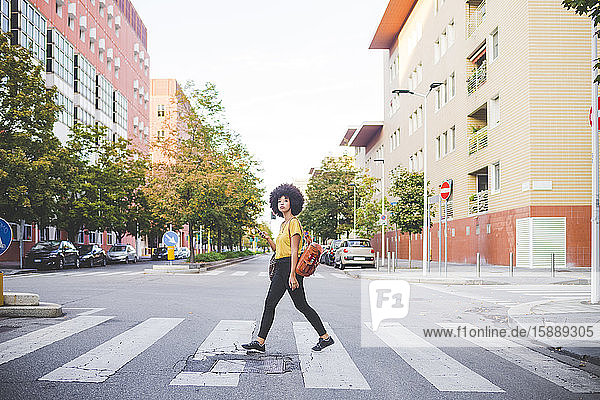 Junge Frau mit Afrofrisur geht in der Stadt spazieren