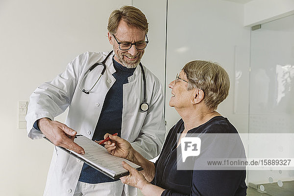 Arzt hilft älterem Patienten beim Ausfüllen des Dokuments