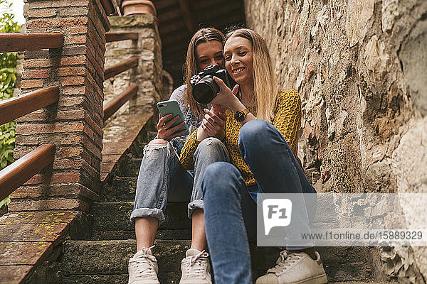 Zwei junge Frauen sitzen auf einer Treppe und schauen in die Kamera  Greve in Chianti  Toskana  Italien