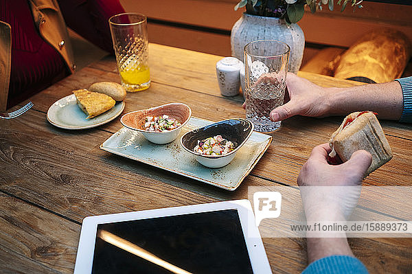 Zwei Personen sitzen im Restaurant  essen und trinken  mit digitalem Tablett auf dem Tisch