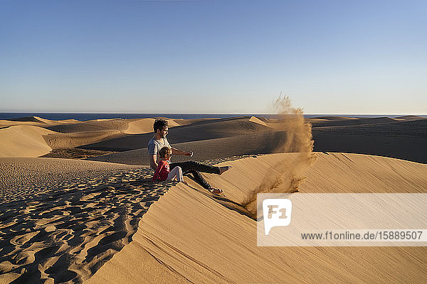 Father and daughter sitting on sand dune  Gran Canaria  Spain