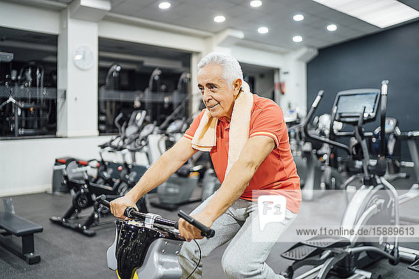 Senior man practising at exercise machine in gym