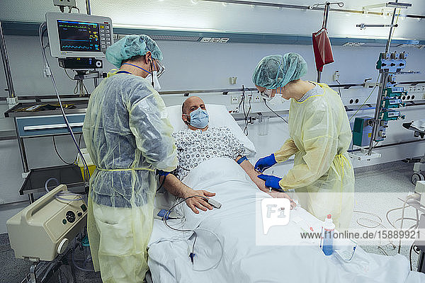 Doctors caring for patient in emergency care unit of a hospital taking blood sample