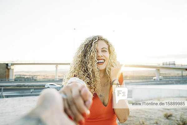 Portrait of happy young woman holding hands at evening twilight
