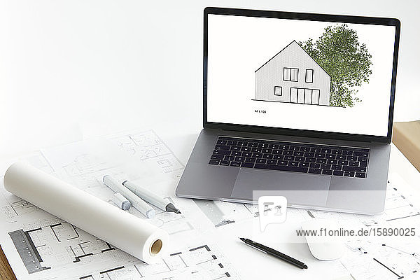 Architekturmodell des Wohneigentums mit Baum auf dem Bildschirm eines Laptops  Bauplan