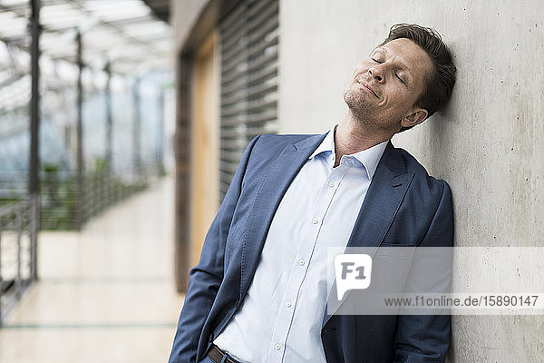 Businessman relaxing with eyes closed  leaning on wall