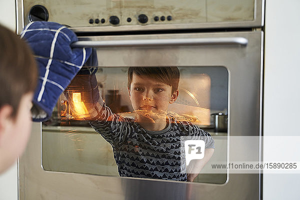 Spiegelbild eines stolzen Jungen  der Kuchen im Ofen anschaut