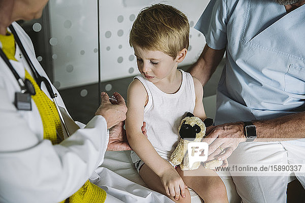 Pediatrist injecting vaccine into arm of toddler