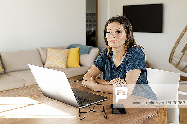 Junge Frau  die von zu Hause am Laptop arbeitet  im Home-Office im modernen Wohnzimmer