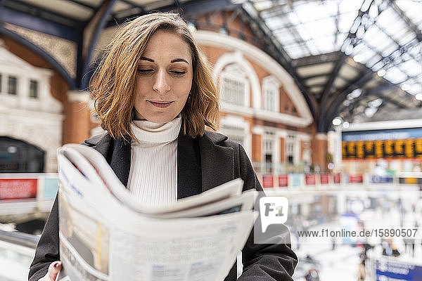 Frau am Bahnhof  die eine Zeitung liest  London  UK