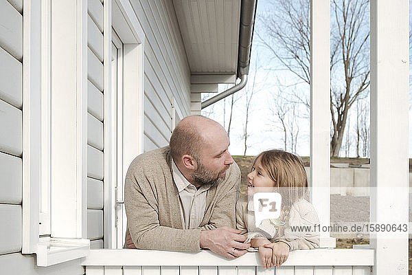 Father and his smiling daughter on porch of their house