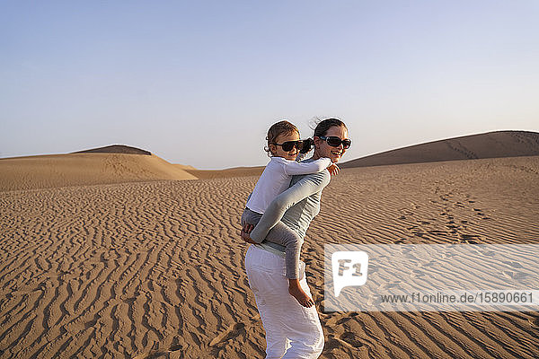 Mutter trägt Tochter huckepack in Sanddünen  Gran Canaria  Spanien