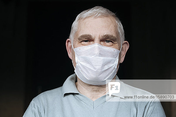 Porträt eines älteren Mannes  der zu Hause eine Maske trägt