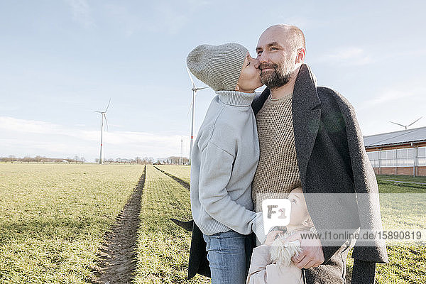 Glückliche Eltern mit einer kleinen Tochter  die im Winter auf einem Feld stehen