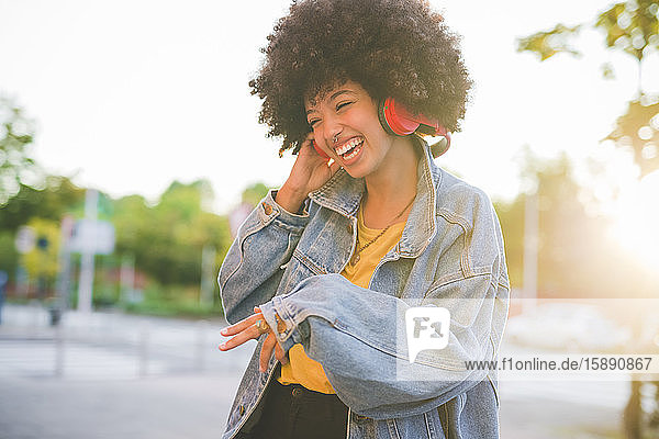 Happy young woman with afro hairdo dancing in the city