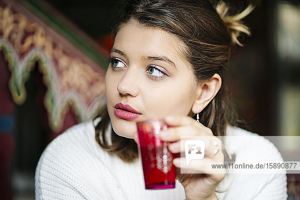 Porträt einer jungen Frau  die in einem Teegeschäft Tee trinkt