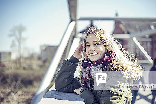 Porträt einer lächelnden jungen Frau auf einer Brücke in der Stadt