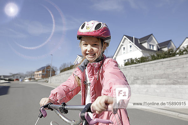 Porträt eines glücklichen kleinen Mädchens mit Fahrrad in einem Wohngebiet