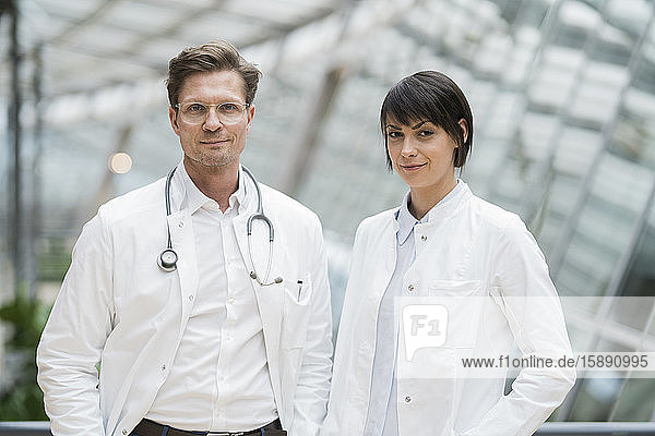 Two confident doctors standing in atrium