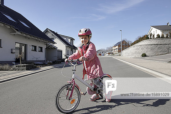 Porträt eines kleinen Mädchens mit Fahrrad in einem Wohngebiet