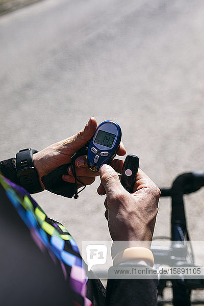 Nahaufnahme eines diabetischen Radfahrers bei der Kontrolle seines Zuckerspiegels