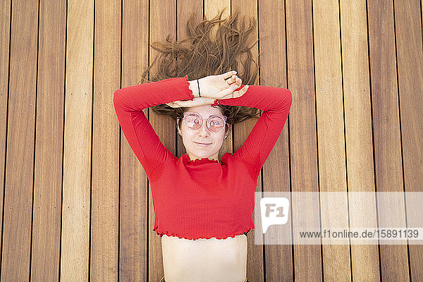 Porträt einer attraktiven jungen Frau  die auf einer Holzterrasse liegt