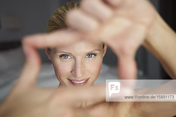 Porträt einer lächelnden schönen Frau beim Herstellen eines Fingerrahmens