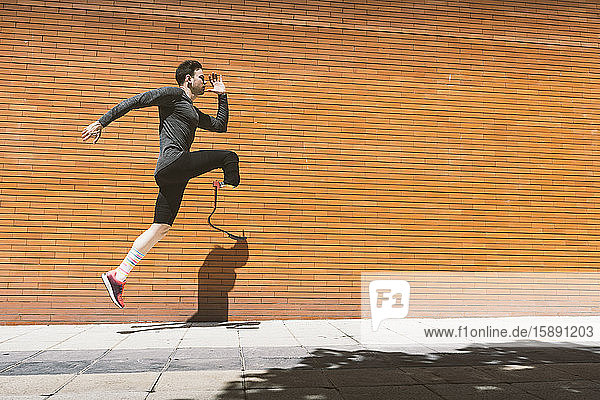 Disabled athlete with leg prosthesis exercising in the city jumping on pavenemt