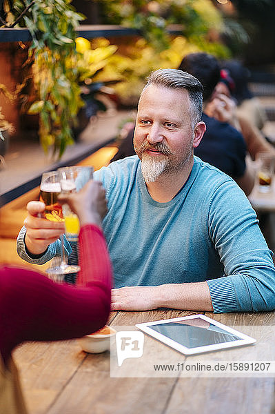 Reifer Mann sitzt im Restaurant und trinkt mit einem Freund