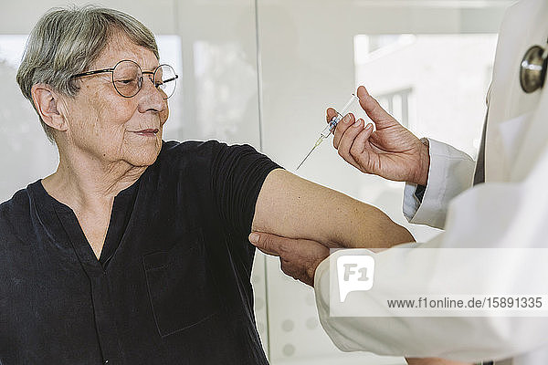 Arzt injiziert Impfstoff in den Arm eines älteren Patienten