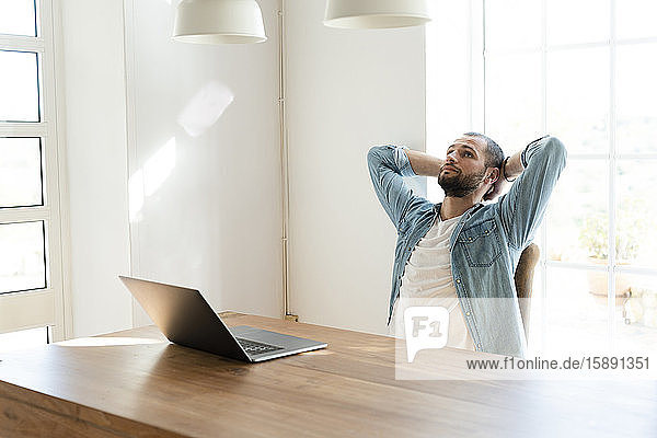 Schwerer junger Mann mit Laptop im Home-Office macht eine Pause
