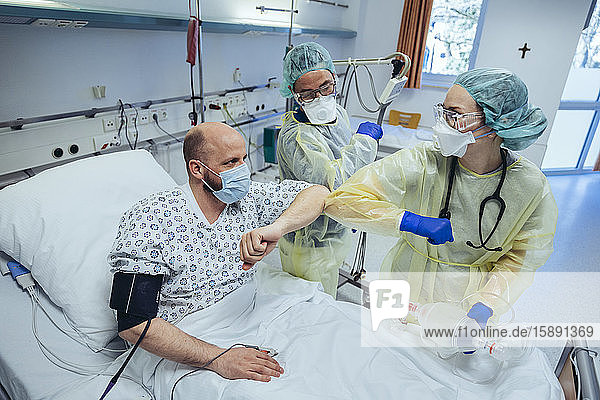 Ärzte machen Ellbogenstoß mit geheiltem Patienten auf der Notfallstation eines Krankenhauses