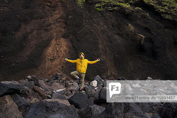 Man standing amidst volcanic rocks in yoga pose  Sao Miguel Island  Azores  Portugal