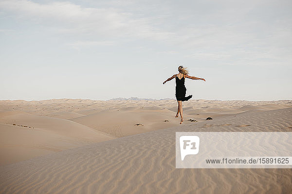 Rückenansicht einer blonden Frau  die in die Luft springt  Algodones Dunes  Brawley  USA
