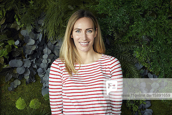 Porträt einer lächelnden Frau vor einer grünen Wand