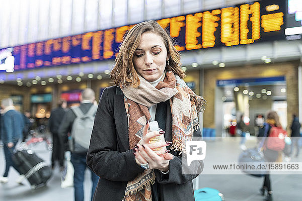 Woman using sanitising hand gel at train station