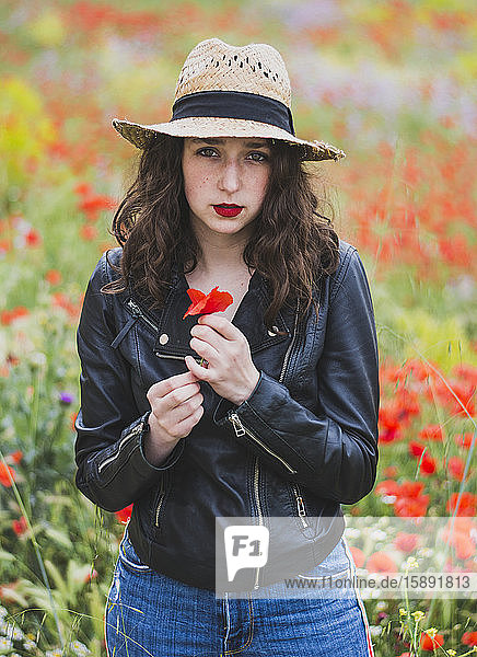 Bildnis einer jungen Frau mit roten Lippen im Mohnfeld stehend