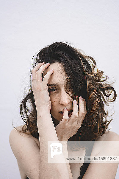 Portrait of young woman with hands on her face