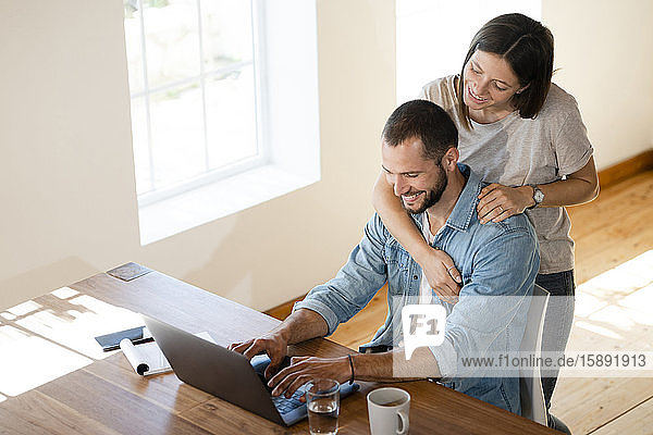 Glückliches junges Paar benutzt Laptop zu Hause