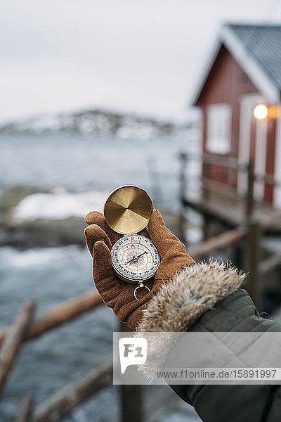 Close-up of hand holding compass at the coast  Lofoten  Norway