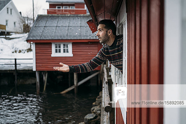 Tourist  der sich aus dem Fenster einer Hütte lehnt  Lofoten  Norwegen