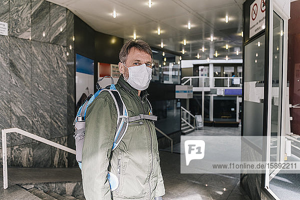 Man with mask standing in entrance of shut down shopping center