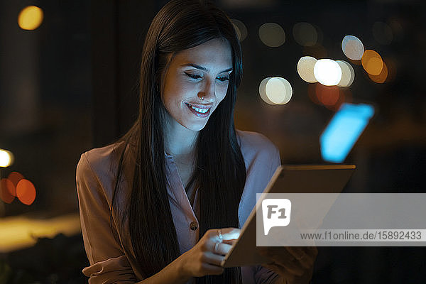 Porträt einer lächelnden jungen Frau mit digitalem Tablett im Büro