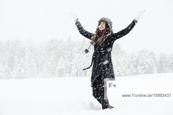 Portrait of happy young woman dancing in winter landscape