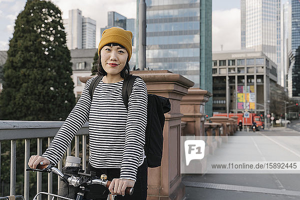 Portrait of confident woman with bicycle in the city  Frankfurt  Germany