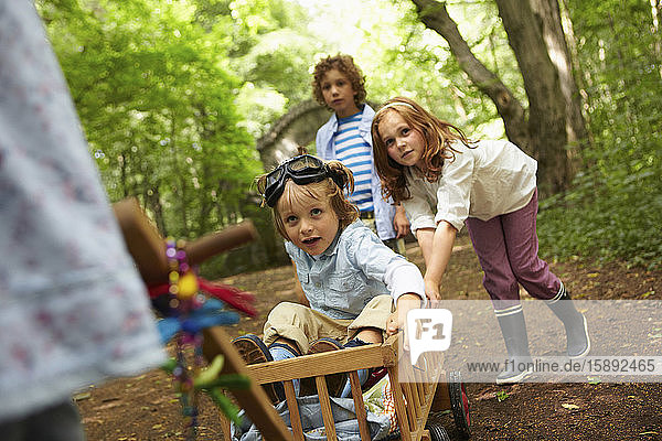 Kinder mit Handwagen spielen im Wald