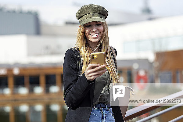 Porträt einer glücklichen jungen Frau  die auf ein Handy schaut
