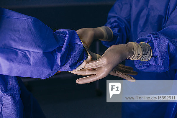 OP-Schwester hilft dem Chirurgen beim Anziehen der Handschuhe vor einer Operation